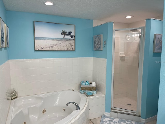 bathroom with tile patterned floors, independent shower and bath, and a textured ceiling