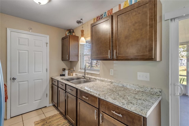 kitchen featuring light stone countertops, sink, dark brown cabinets, and light tile patterned floors