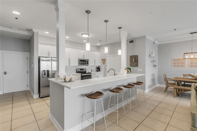 kitchen featuring appliances with stainless steel finishes, white cabinetry, a kitchen breakfast bar, hanging light fixtures, and light tile patterned floors