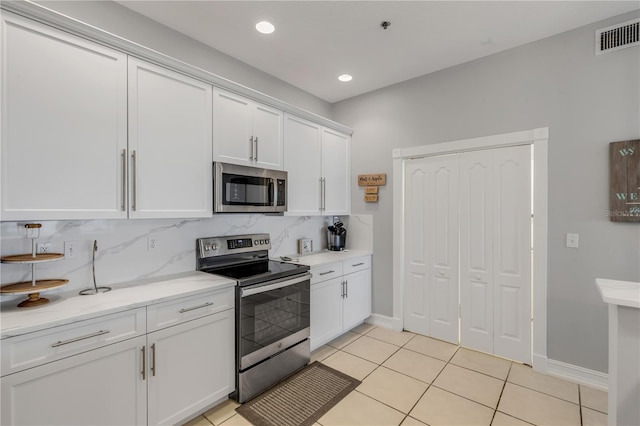 kitchen with white cabinetry, light tile patterned floors, backsplash, and appliances with stainless steel finishes