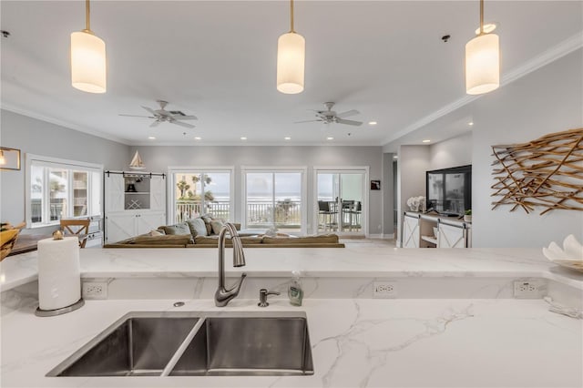 kitchen with hanging light fixtures, a wealth of natural light, ornamental molding, and sink