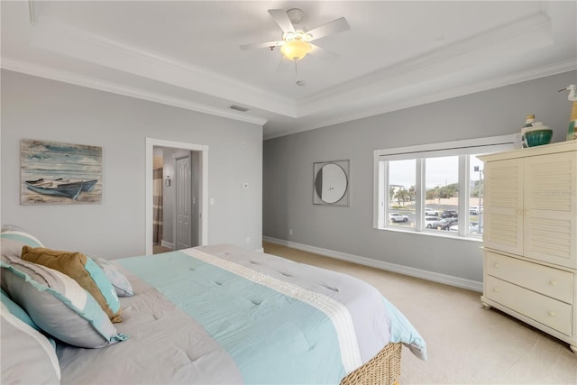 carpeted bedroom with ornamental molding, a raised ceiling, ceiling fan, and ensuite bathroom