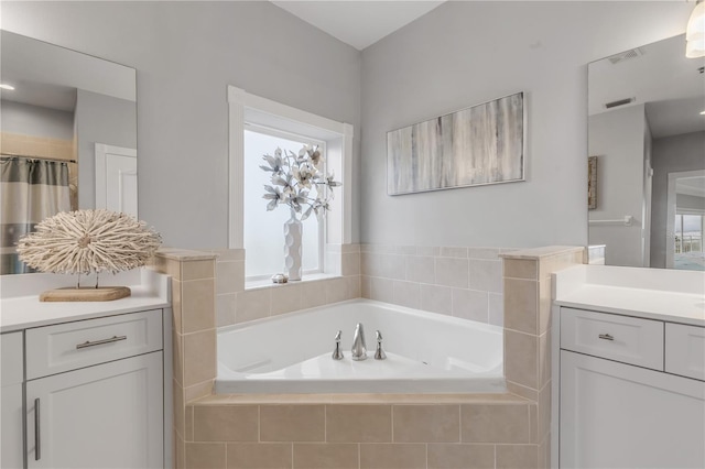 bathroom featuring vanity and tiled bath