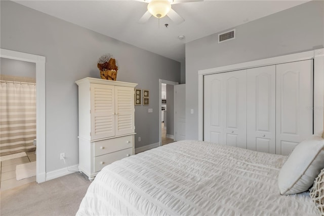 carpeted bedroom featuring a closet, ceiling fan, and ensuite bathroom