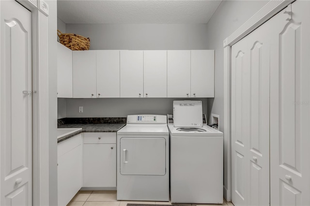 clothes washing area with cabinets, light tile patterned floors, a textured ceiling, and independent washer and dryer