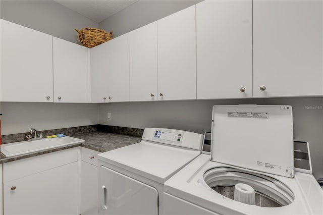 laundry room with sink, washing machine and dryer, and cabinets