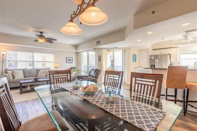 dining area with ceiling fan, light hardwood / wood-style floors, and a textured ceiling