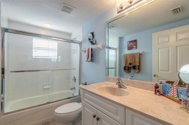 full bathroom with vanity, bath / shower combo with glass door, toilet, and a textured ceiling