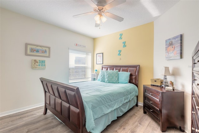 bedroom featuring ceiling fan, light hardwood / wood-style flooring, and a textured ceiling