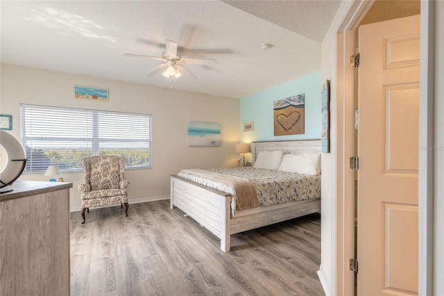 bedroom featuring ceiling fan, wood-type flooring, and a textured ceiling