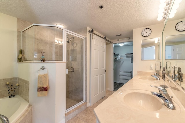 bathroom with tile patterned floors, separate shower and tub, vanity, and a textured ceiling