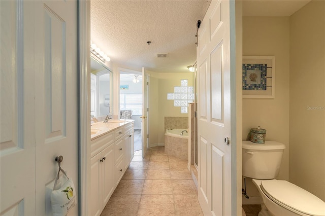 bathroom featuring toilet, a textured ceiling, vanity, tiled bath, and tile patterned flooring