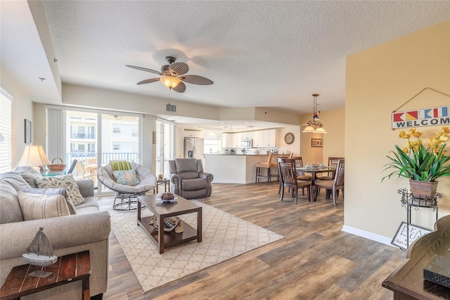 living room with ceiling fan, hardwood / wood-style flooring, and a textured ceiling