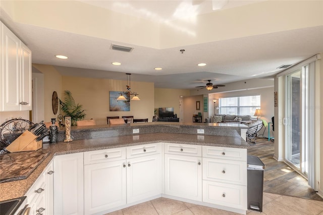 kitchen featuring light tile patterned floors, stainless steel electric stove, kitchen peninsula, and white cabinets