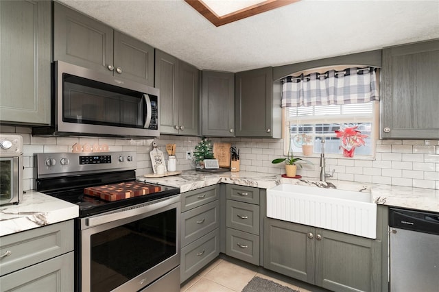 kitchen with stainless steel appliances, light tile patterned flooring, sink, and decorative backsplash