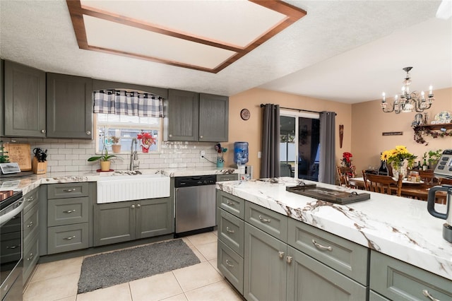 kitchen featuring pendant lighting, sink, light tile patterned floors, appliances with stainless steel finishes, and tasteful backsplash