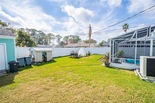 view of yard featuring a fenced in pool, a lanai, central AC, and a storage unit