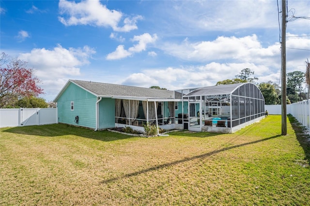 rear view of house with a yard and glass enclosure