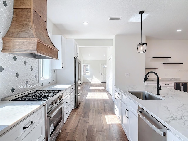 kitchen featuring decorative light fixtures, sink, white cabinets, custom exhaust hood, and high end appliances