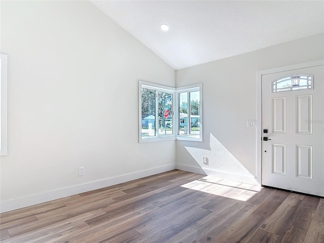 foyer entrance featuring hardwood / wood-style flooring, lofted ceiling, and a textured ceiling