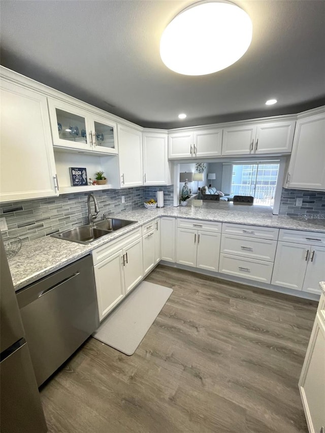 kitchen with sink, dark wood-type flooring, dishwasher, white cabinetry, and backsplash