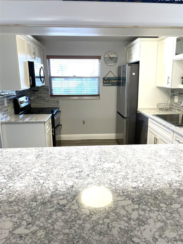 kitchen featuring white cabinetry, sink, light stone counters, and stainless steel appliances