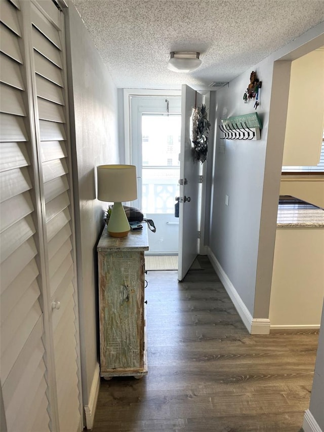 hallway with dark hardwood / wood-style flooring and a textured ceiling