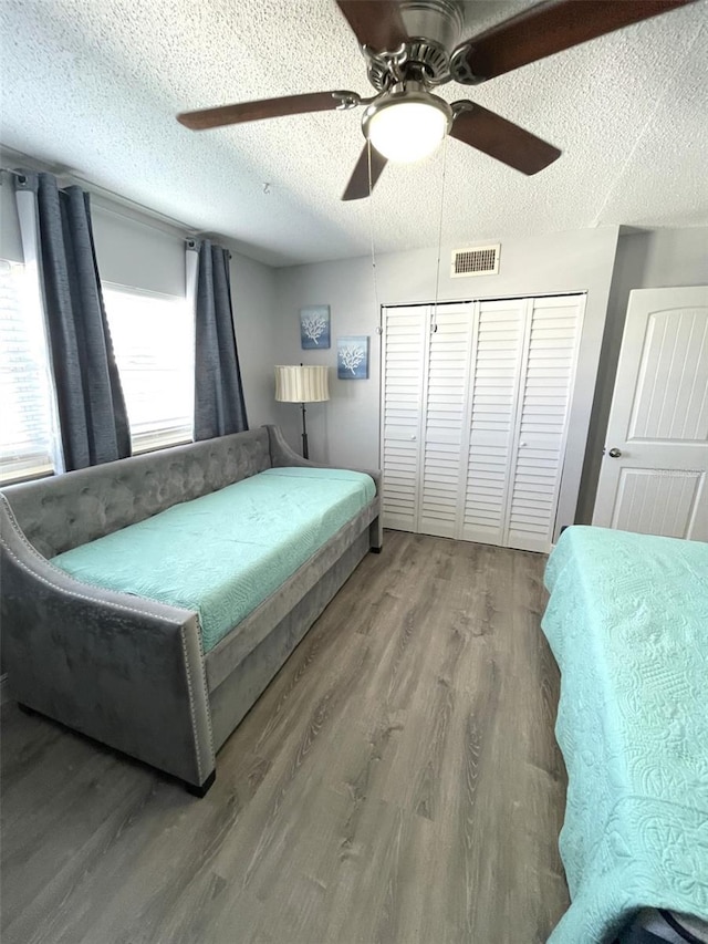 bedroom featuring hardwood / wood-style flooring, a closet, ceiling fan, and a textured ceiling