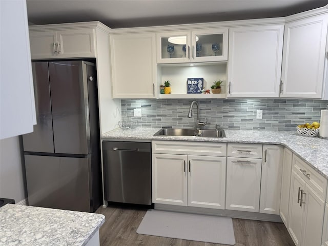 kitchen with sink, stainless steel refrigerator, dishwasher, light stone countertops, and white cabinets