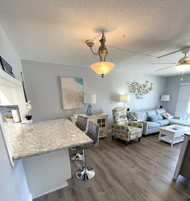 living room featuring a textured ceiling, dark wood-type flooring, and ceiling fan