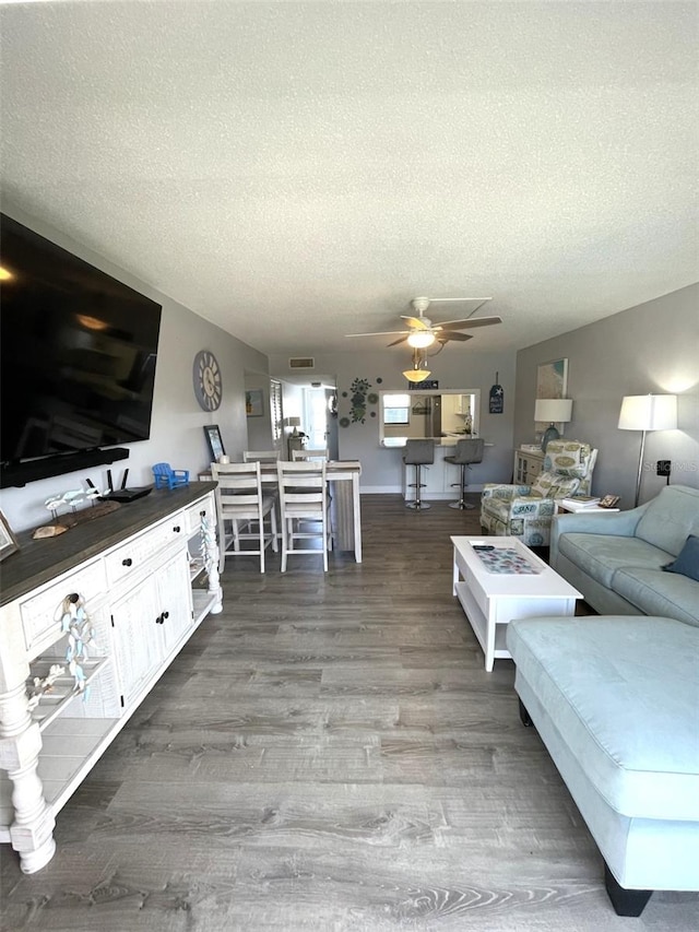 living room featuring ceiling fan, hardwood / wood-style flooring, and a textured ceiling