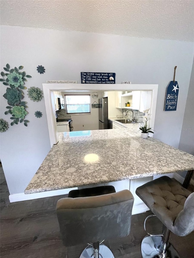 kitchen featuring stainless steel appliances, sink, a textured ceiling, and kitchen peninsula