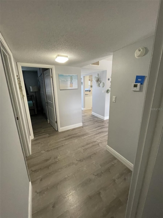 hallway with wood-type flooring and a textured ceiling