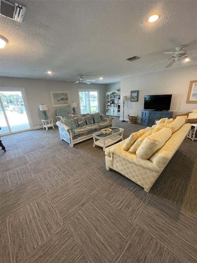 carpeted living room featuring a healthy amount of sunlight, a textured ceiling, and ceiling fan