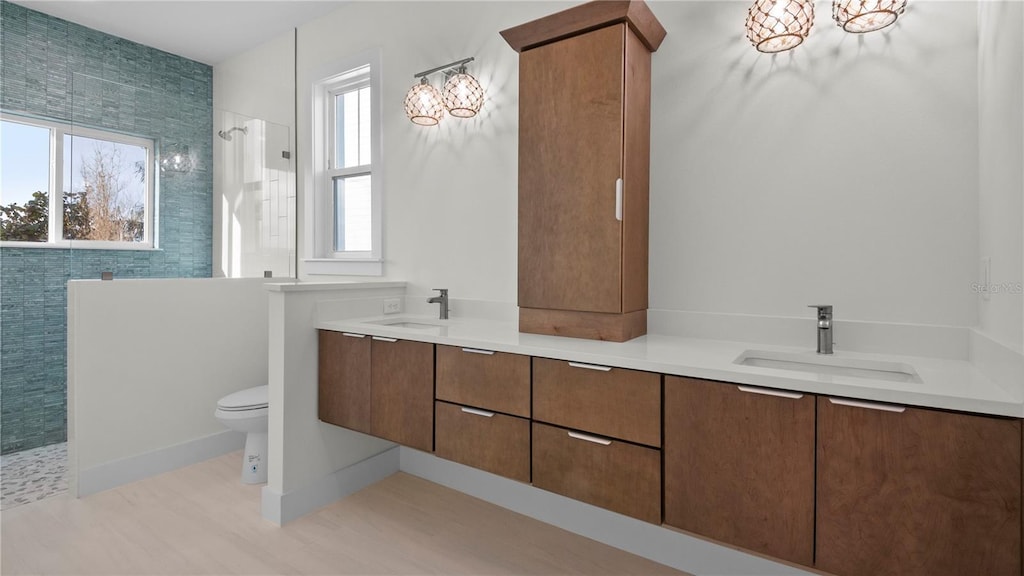 bathroom featuring vanity, a tile shower, and toilet