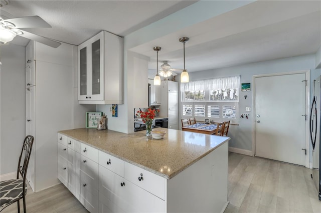 kitchen featuring light stone countertops, light wood-type flooring, white cabinets, and ceiling fan