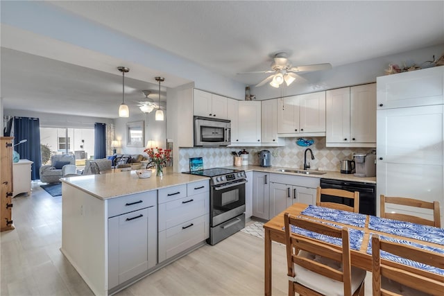 kitchen with appliances with stainless steel finishes, pendant lighting, sink, white cabinets, and ceiling fan