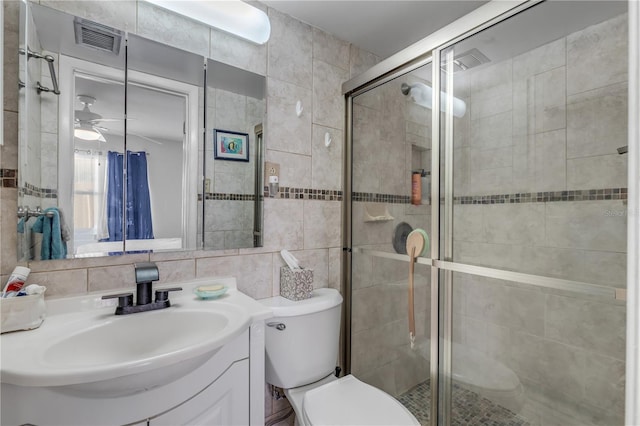 bathroom with vanity, toilet, an enclosed shower, and tile walls