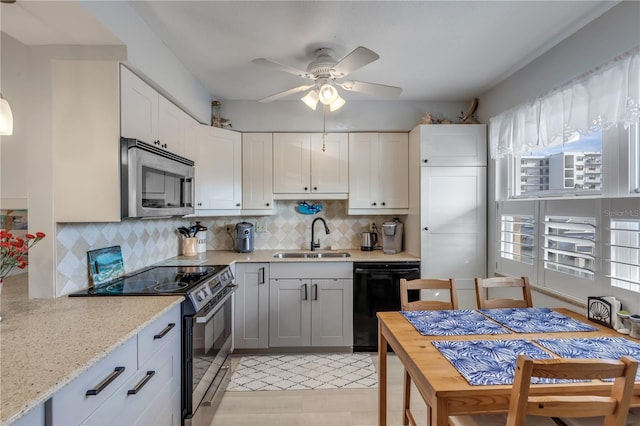 kitchen featuring sink, light stone counters, tasteful backsplash, stainless steel appliances, and white cabinets