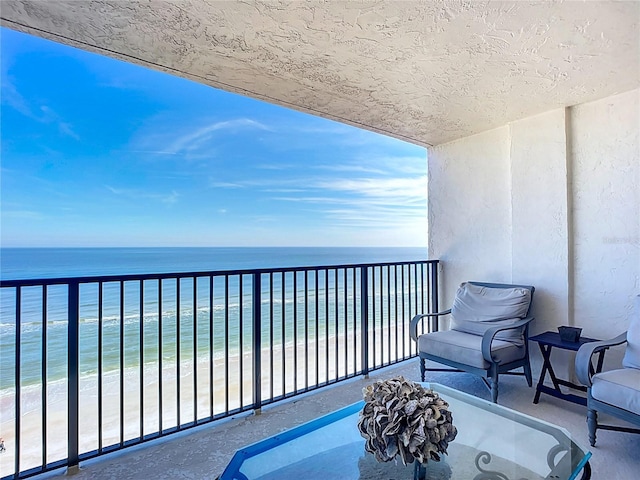 balcony with a water view and a view of the beach