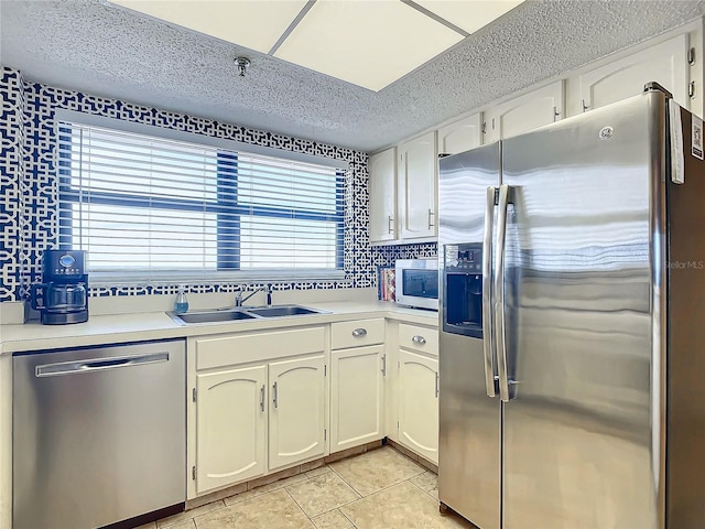 kitchen featuring sink, white cabinetry, stainless steel appliances, a textured ceiling, and decorative backsplash