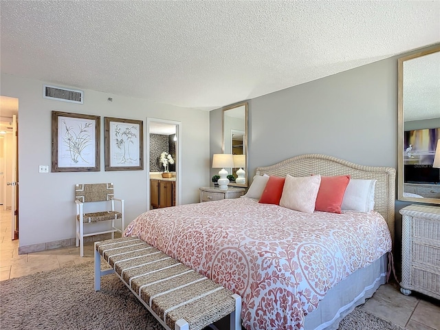 bedroom with a textured ceiling and ensuite bath