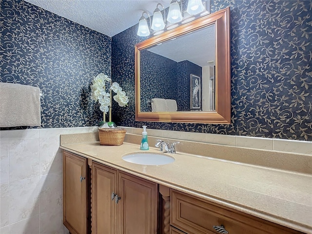 bathroom featuring vanity, a textured ceiling, and tile walls