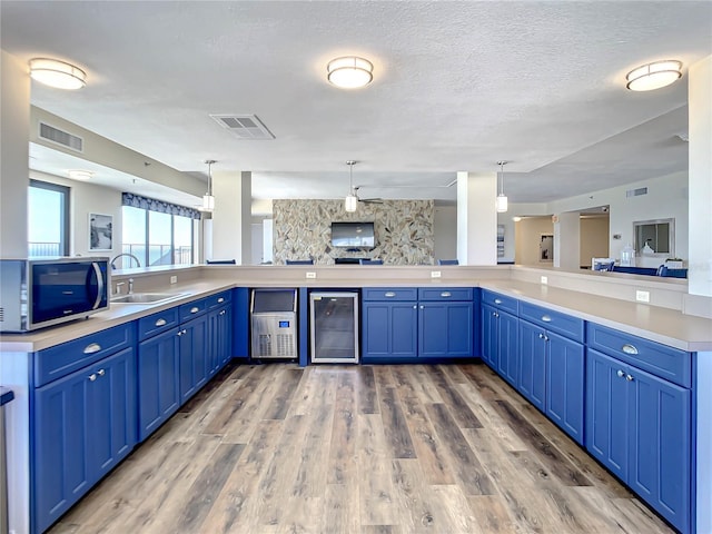 kitchen featuring wine cooler, sink, pendant lighting, and blue cabinetry