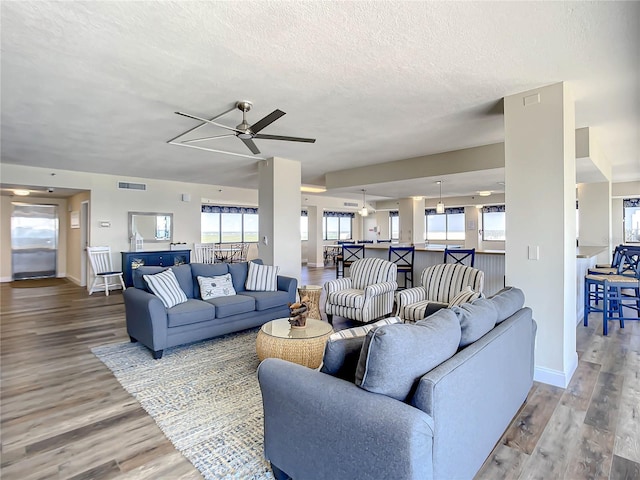 living room featuring ceiling fan, wood-type flooring, and a textured ceiling