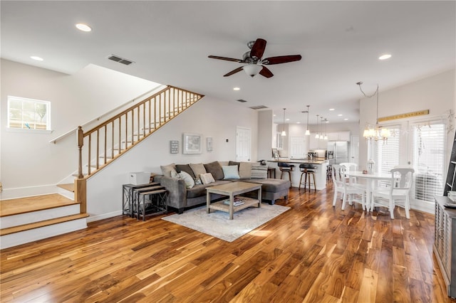 living room featuring hardwood / wood-style flooring and ceiling fan with notable chandelier