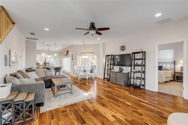 living room featuring hardwood / wood-style flooring and ceiling fan with notable chandelier