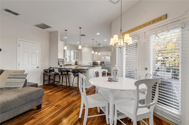 dining area with dark wood-type flooring and an inviting chandelier