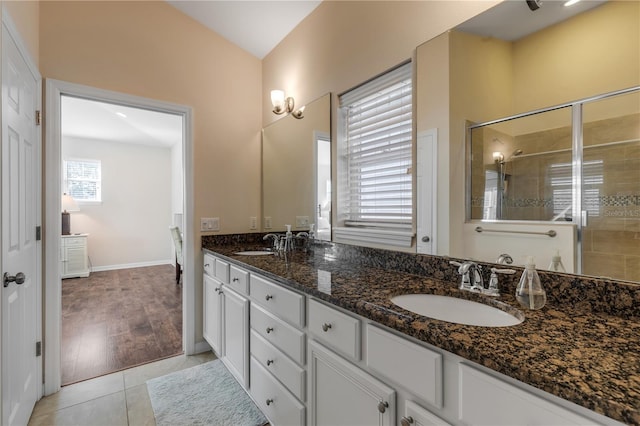 bathroom with walk in shower, vanity, and tile patterned flooring