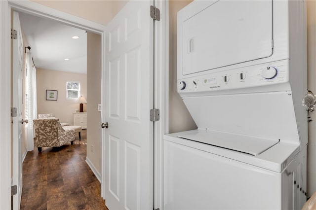 clothes washing area with dark wood-type flooring and stacked washer and clothes dryer